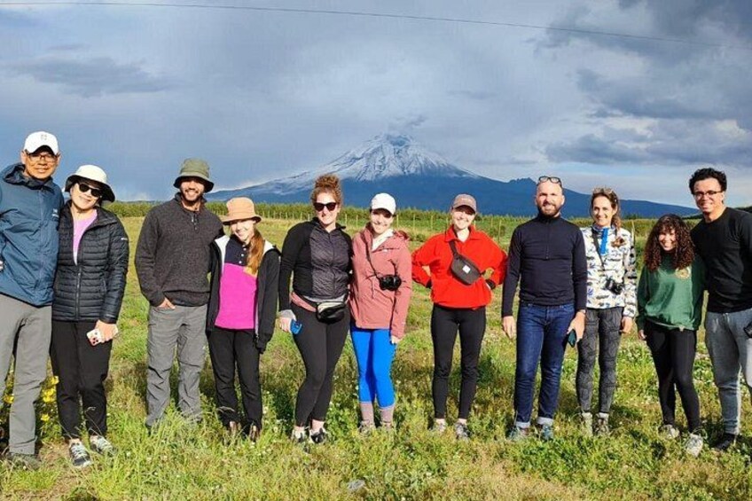 Eine Gruppe von Menschen steht auf einer Wiese, im Hintergrund ist ein Berg zu sehen. 4