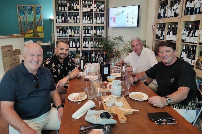 Four people seated at a table with wine glasses, bottles, and a menu. 3