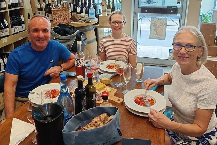 A group of people dining at a restaurant with wine bottles and plates of food on the table. 4