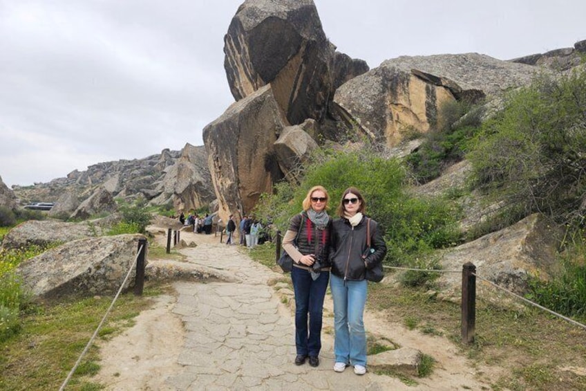 A rocky trail with large boulders and a group of people walking. 3