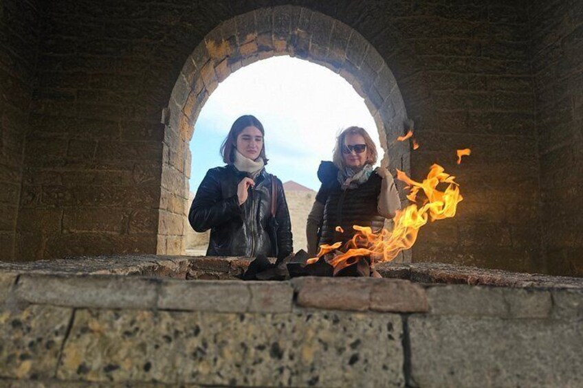 Two people in an arched stone structure with a fire in front of them. 4