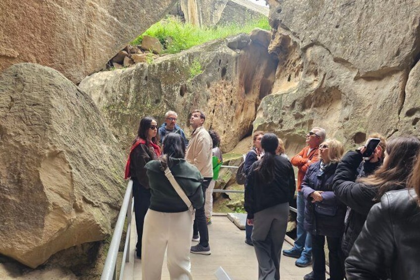 A group of people standing on a path surrounded by large rock formations. 2