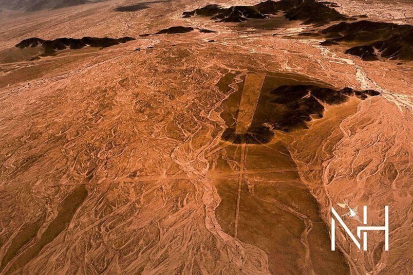 A vast desert landscape with winding roads and a large, dark area that could be a crater or sinkhole. 4