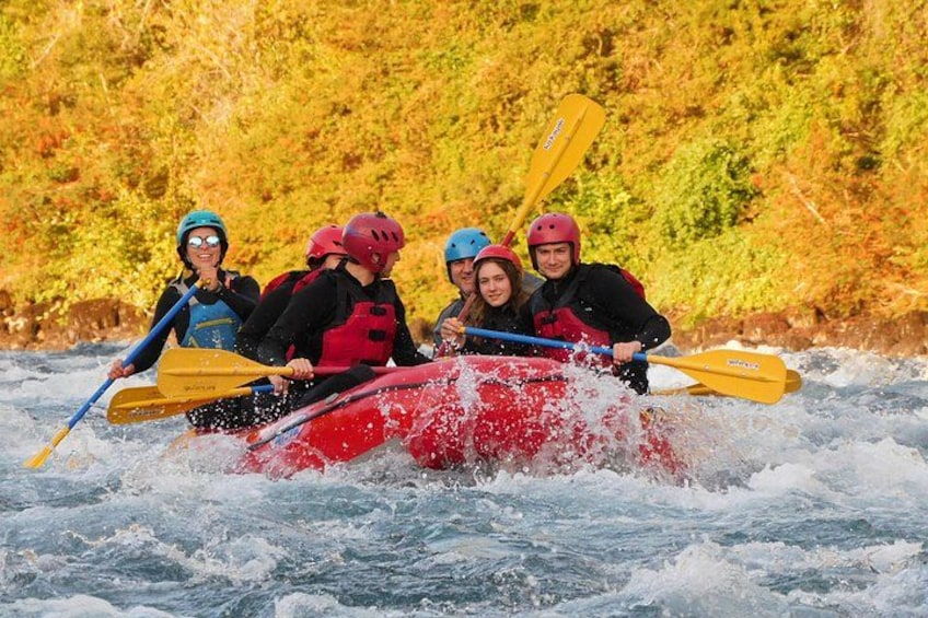 A group of people in a red raft navigating through a river with rapids. 2