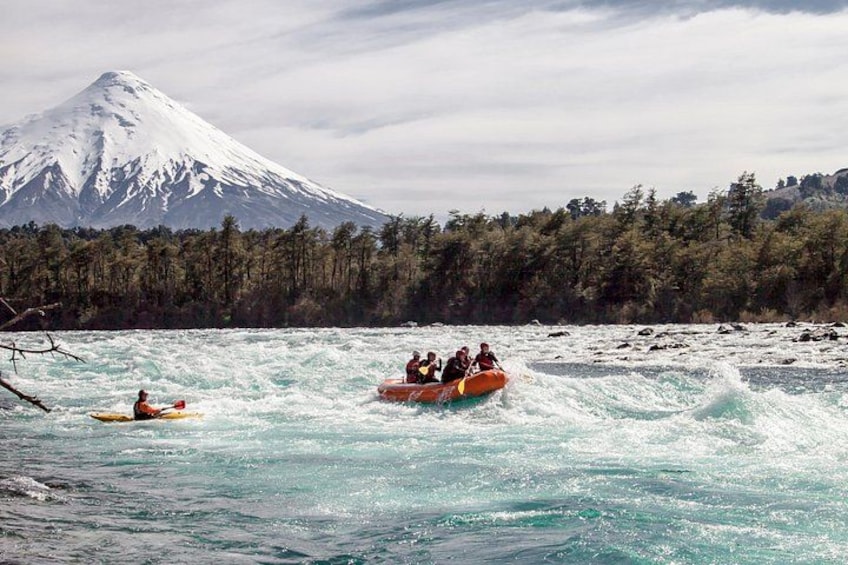 People kayaking on a river with a snow-capped mountain in the background. 3