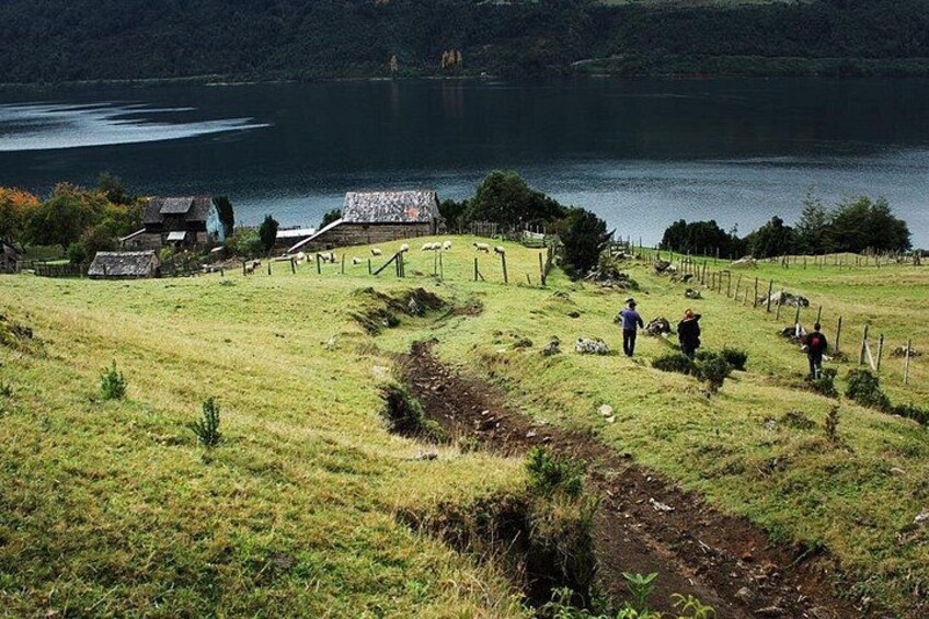 A rural landscape with a lake, a fenced pasture, and a few buildings. 5