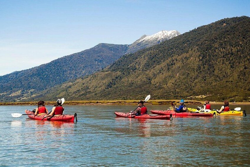 A group of people kayaking on a calm lake with mountains in the background. 4