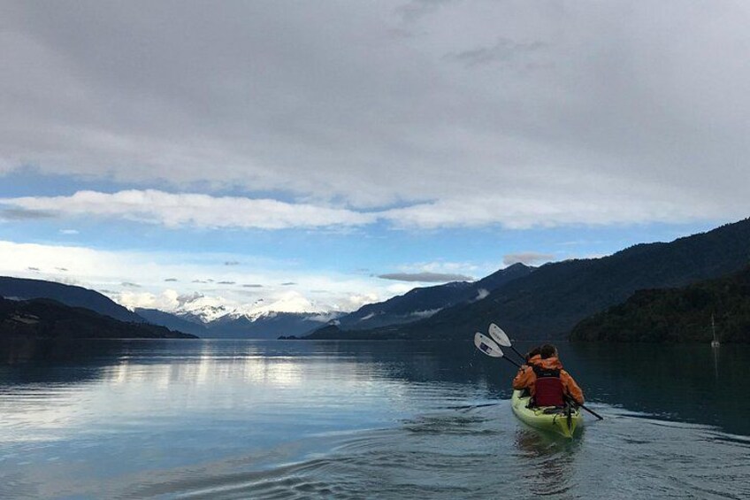 A kayaker in a yellow kayak on a calm lake with mountains in the background. 3