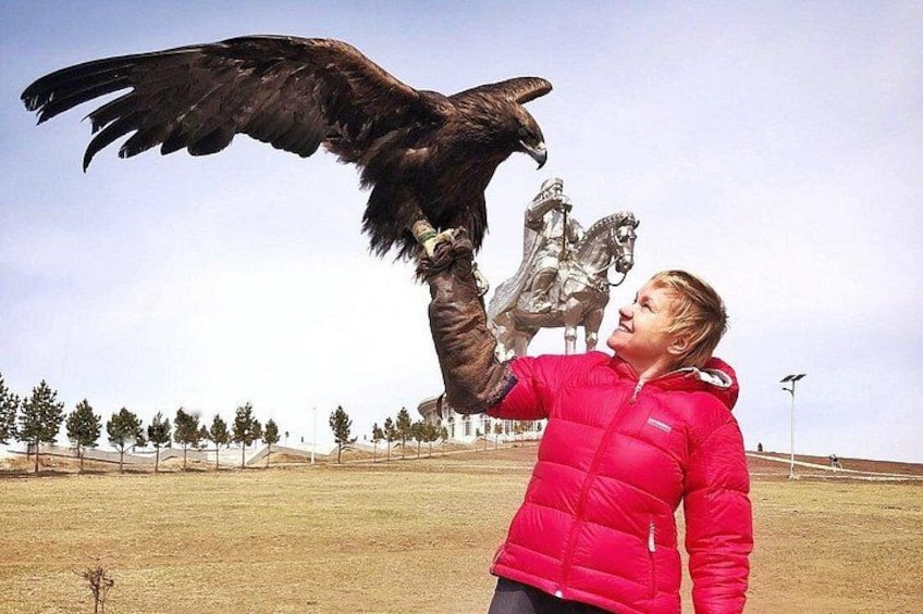 Una persona con una chaqueta roja interactuando con una estatua de un ave rapaz. 4