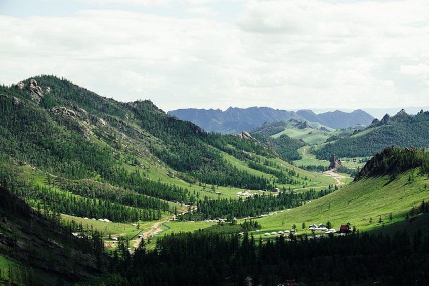 Un paisaje montañoso con un valle, zonas boscosas y una carretera. 2
