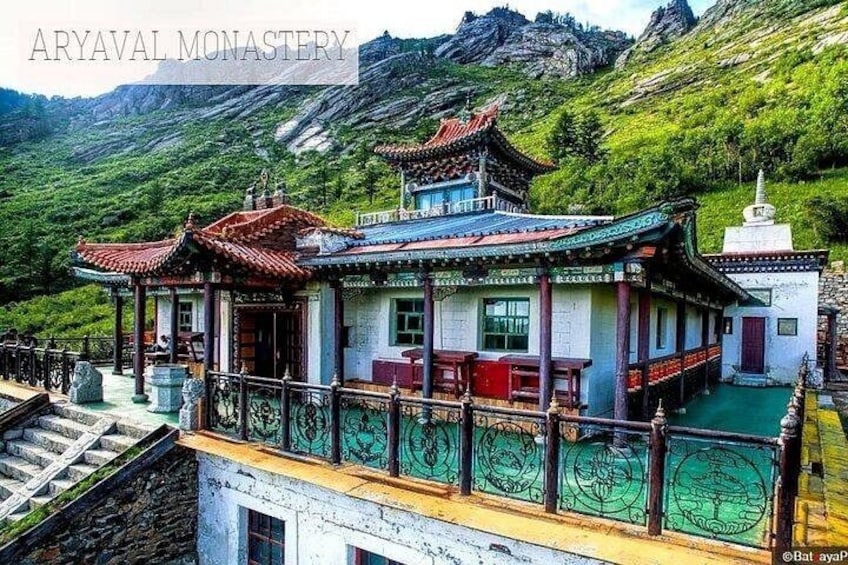 Un edificio tradicional con techo rojo, rodeado de exuberante vegetación y montañas. 3