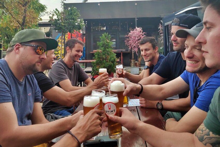 Un grupo de personas brindando con vasos de cerveza en una mesa. 3