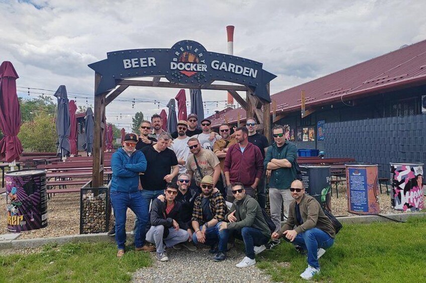Un grupo de personas posando frente a un letrero que dice 'BEER DOCKER GARDEN'. 4