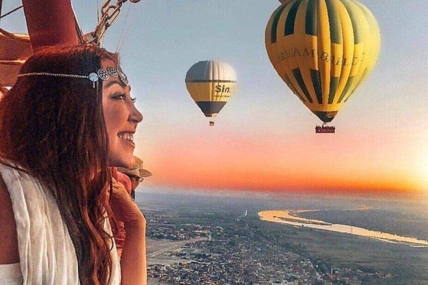 A person overlooking a cityscape with hot air balloons in the distance. 2