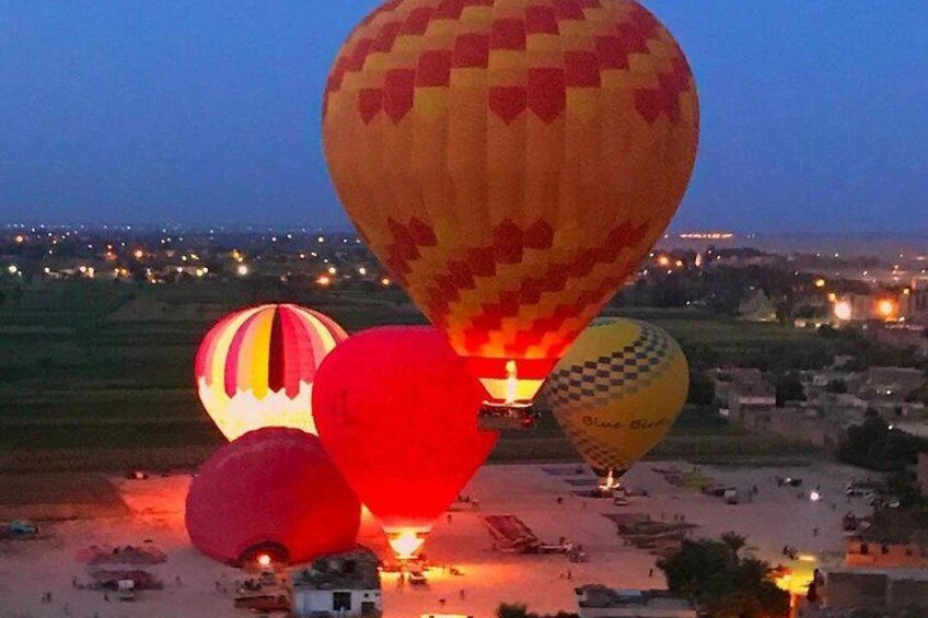 Hot air balloons over a rural landscape with fields and a small settlement in the distance. 5