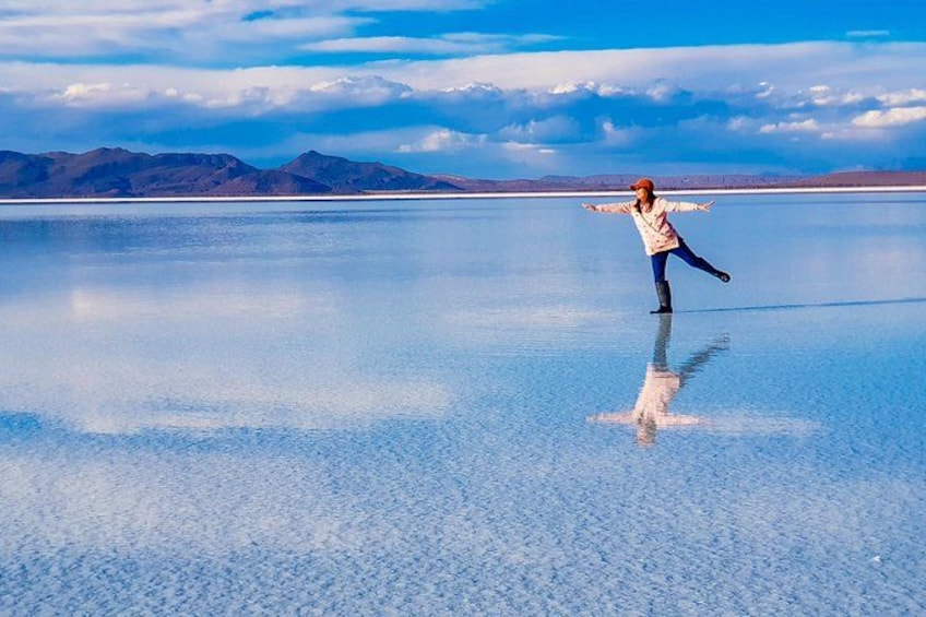 A person ice skating on a frozen lake with mountains in the background. 1
