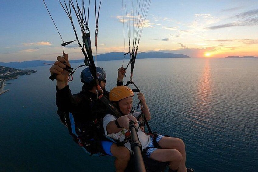 Two people paragliding over a body of water with a sunset in the background. 3