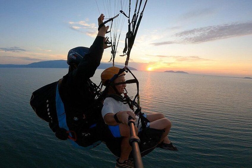 A person paragliding over a body of water with the sun setting in the background. 4