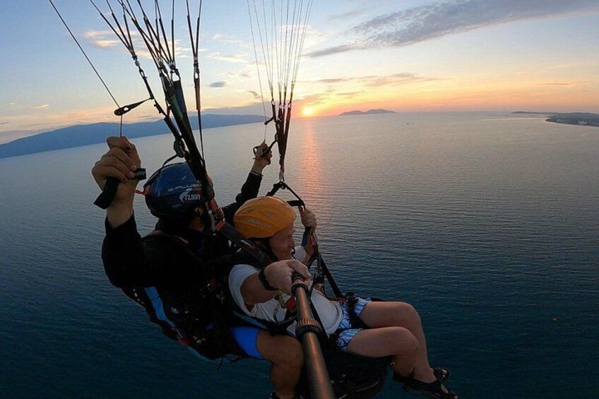 A person paragliding over a body of water during sunset. 5