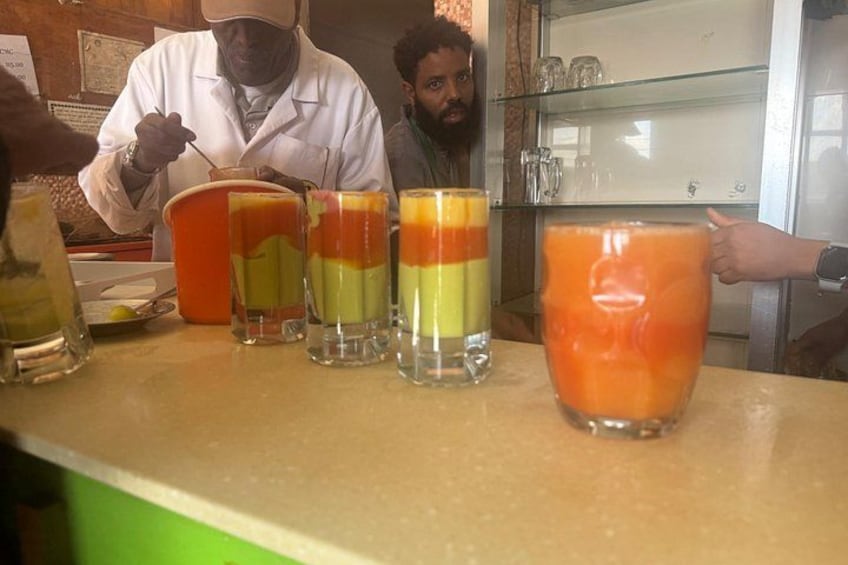 A bar counter with several glasses of layered fruit juice. 3