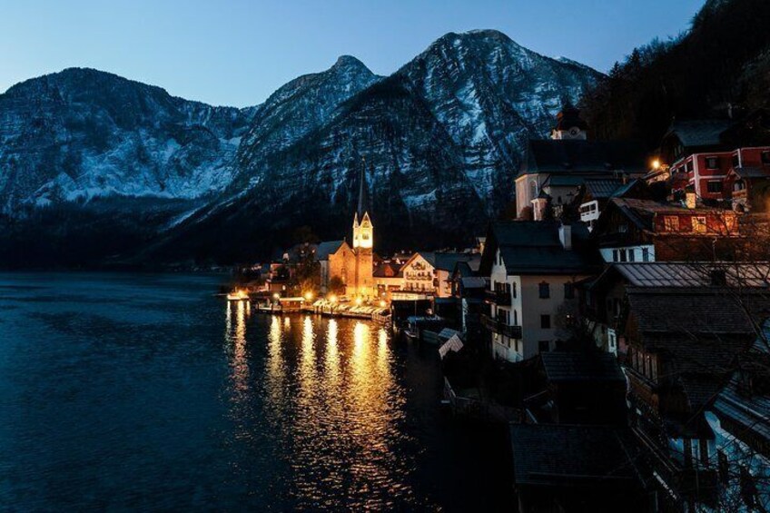 A church with a spire, a mountain, and a lake at dusk. 1