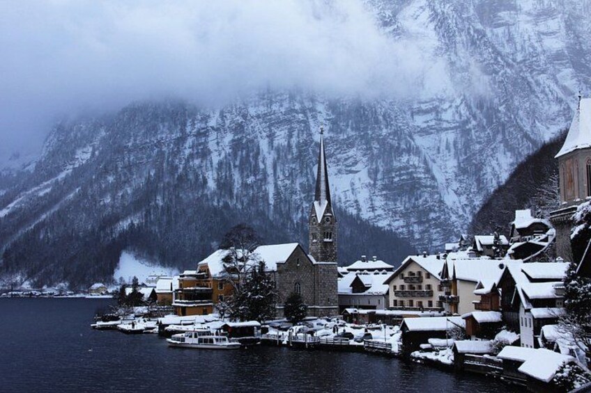 A snow-covered village with a church, boats, and mountains in the background. 5