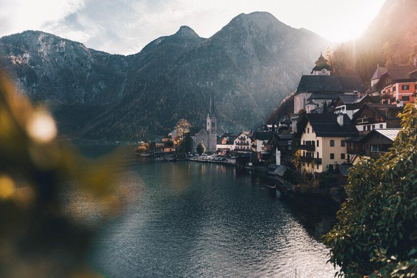 A lakeside town with buildings, a church, and mountains in the background. 2
