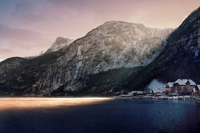 A mountain landscape with a lake, a building, and snow-covered peaks. 4