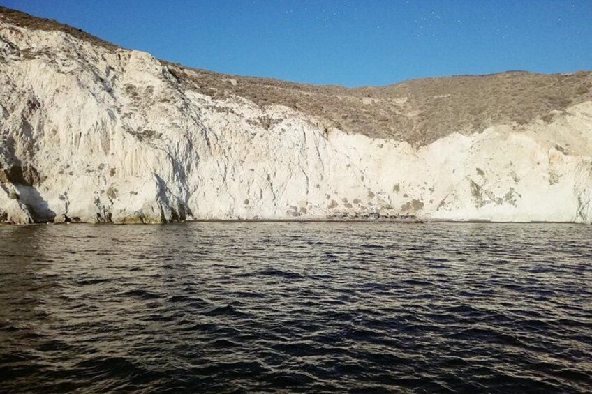 A coastal cliff with a body of water in the foreground. 3