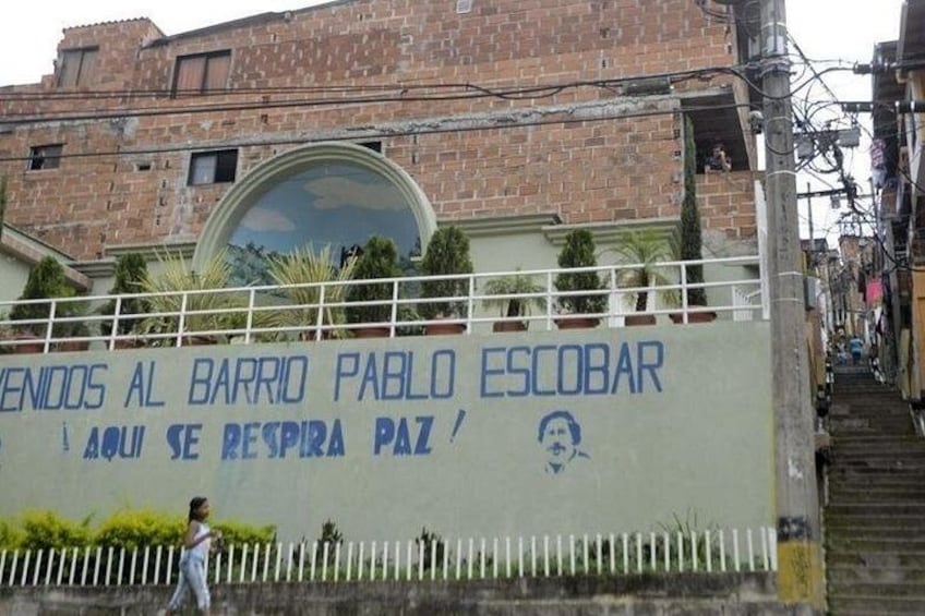 Un edificio con un mural y un letrero que dice 'VENDOOS AL BARRIO PABLO ESCOBAR'. 5