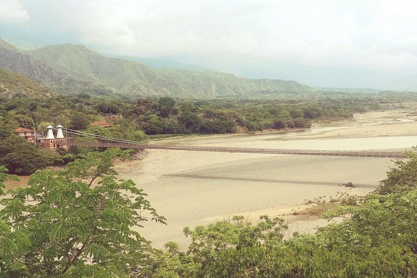 Un río con un puente, rodeado de vegetación y colinas. 5