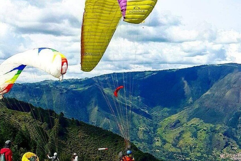 Paraglidingflygare i luften med ett bergigt landskap i bakgrunden. 1