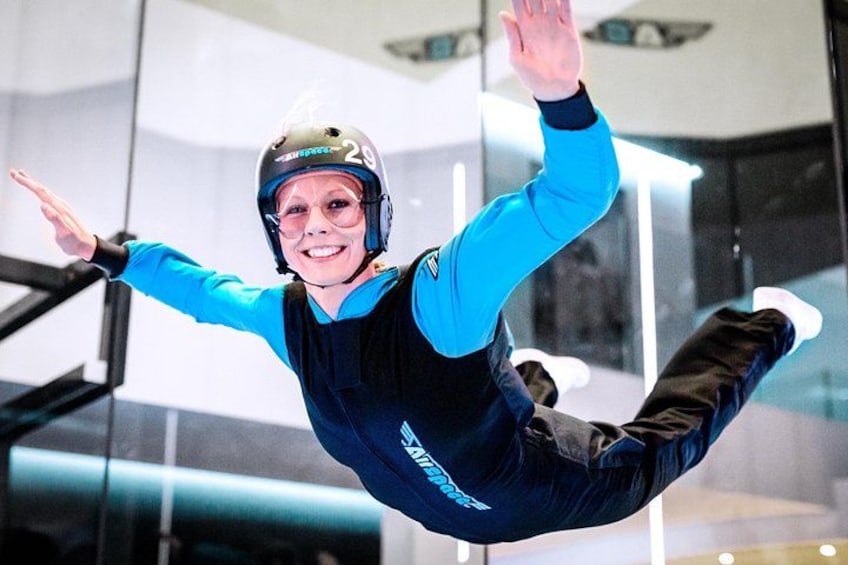 A person in a blue and black skydiving suit mid-air with outstretched arms. 3