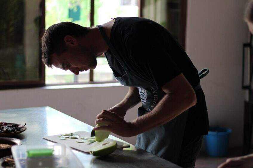 A person slicing a green fruit on a cutting board. 5
