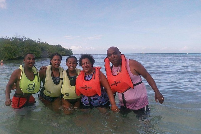 A group of people in a shallow body of water wearing life jackets. 3