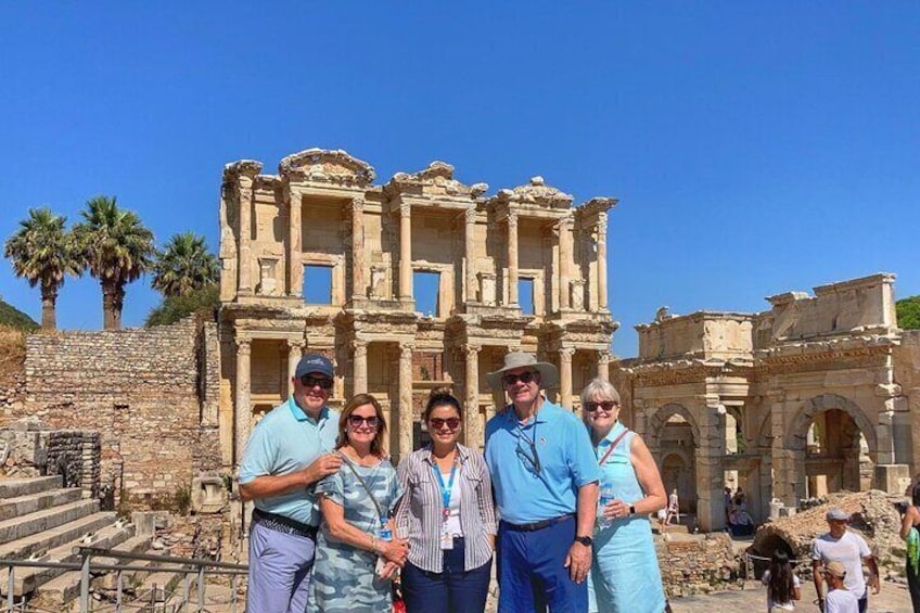 A group of people standing in front of ancient ruins with columns and arches. 1