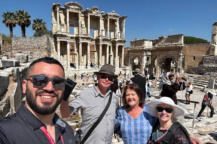 A group of people taking a selfie in front of ancient ruins with columns and arches. 5