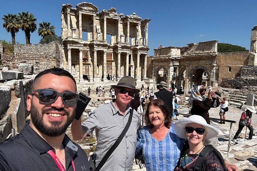 Un groupe de personnes prenant un selfie devant des ruines antiques, avec des colonnes et des arches. 5