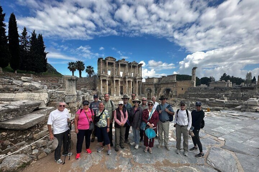 A group of people standing in front of ancient ruins with columns and a large building in the background. 4