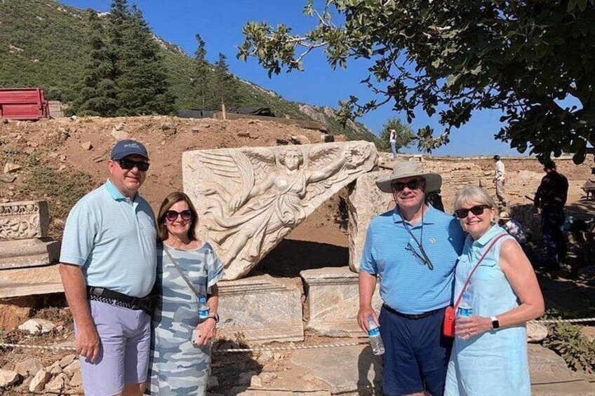 A group of people standing in front of ancient ruins with a large stone carving. 2
