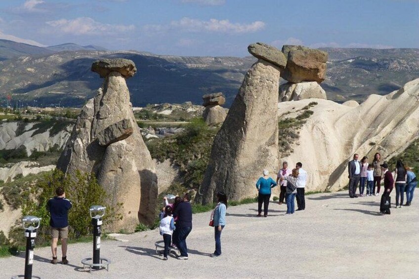 A group of people standing near rock formations with a mountainous landscape in the background. 3