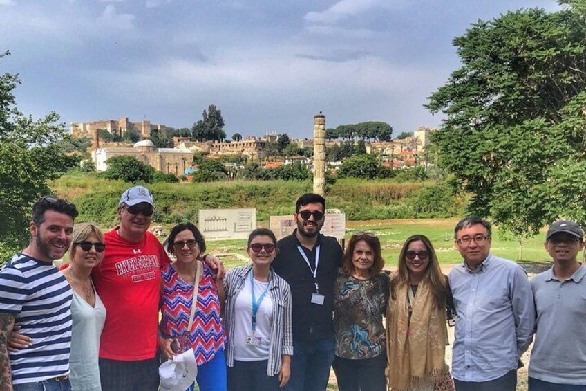 A group of people standing in a park with a historical building in the background. 3