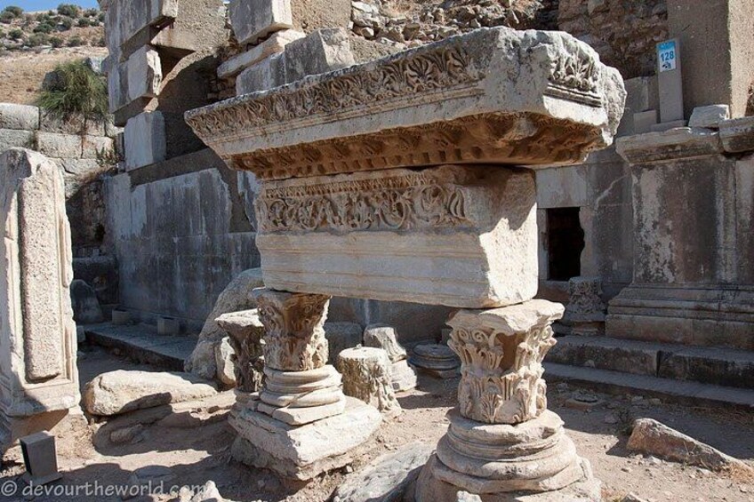 Ancient stone columns and a large stone structure with intricate carvings. 5