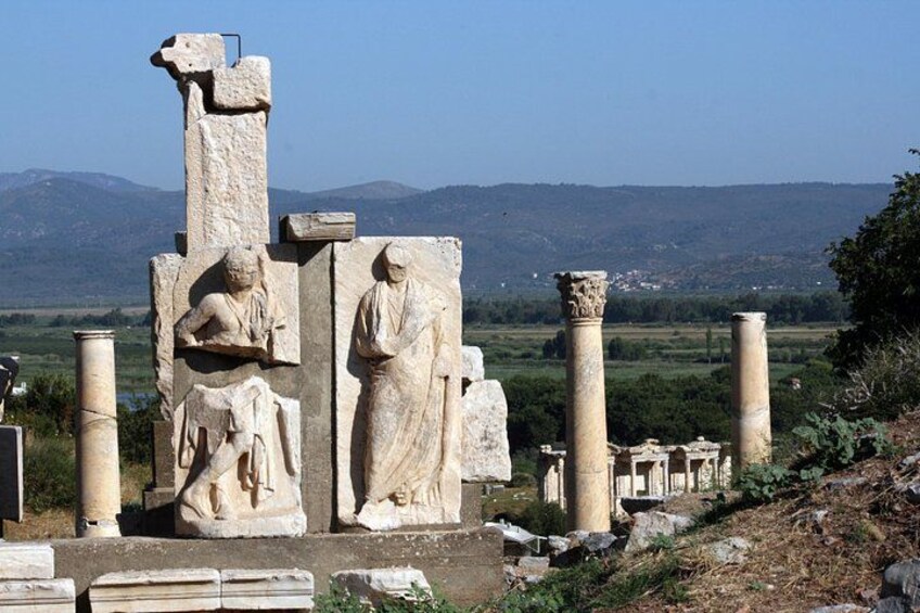 Ancient ruins with stone statues and columns, set against a mountainous backdrop. 4