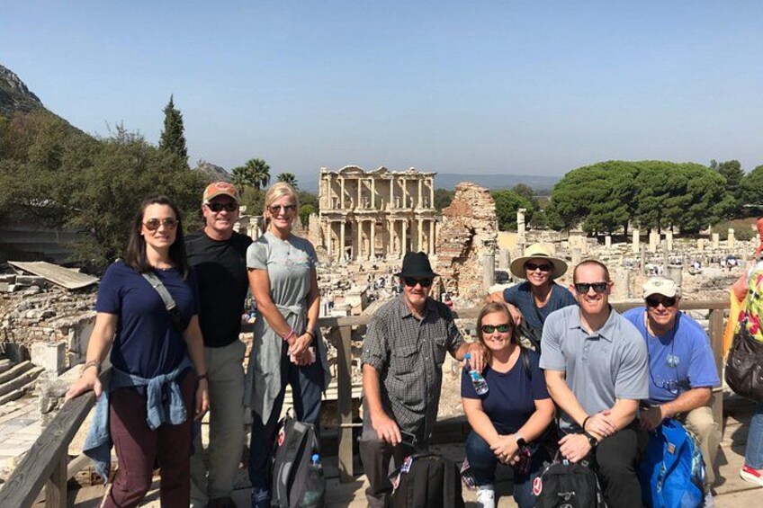 A group of people standing in front of ancient ruins with columns and a large building in the background. 3