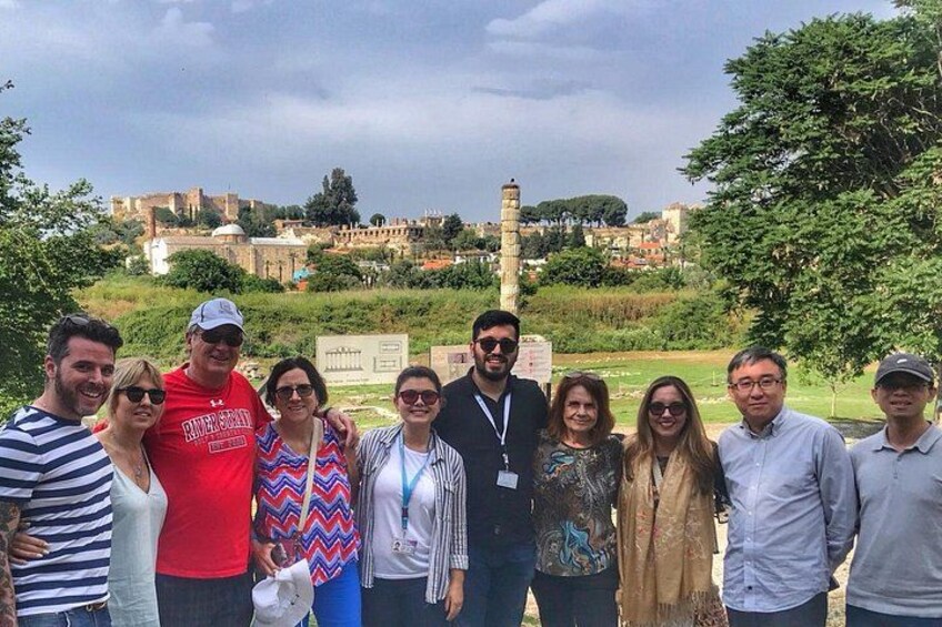 A group of people standing outdoors with a historical building and a tower in the background. 2