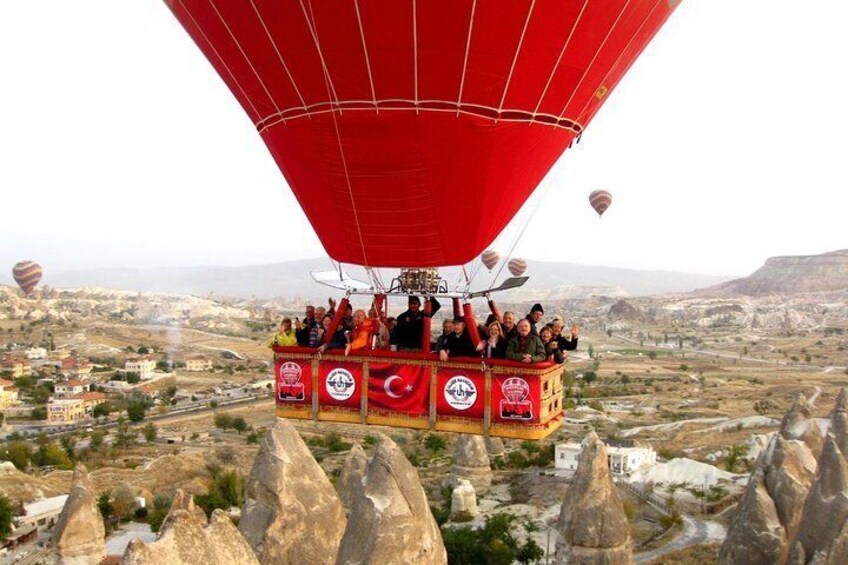 A red hot air balloon with passengers over a rocky landscape. 1