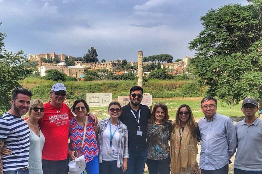 A group of people posing in a park with a historical monument in the background. 4