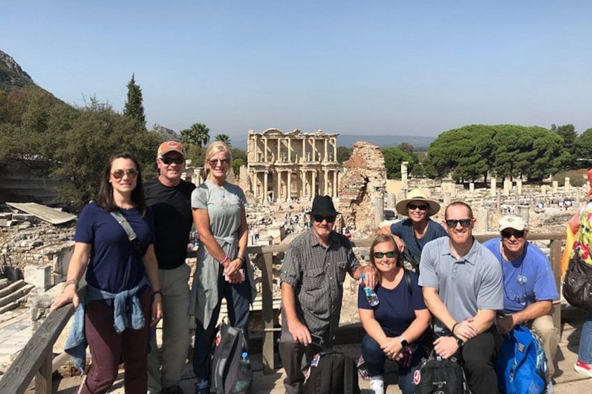 A group of people standing in front of ancient ruins with columns and a large structure in the background. 2