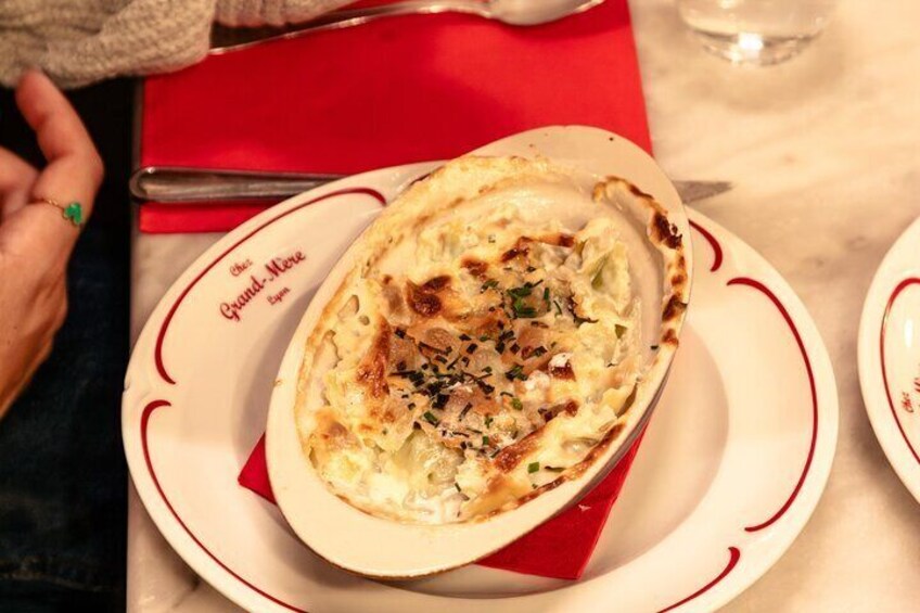 A dish of baked potatoes garnished with herbs on a white plate with red trim. 3